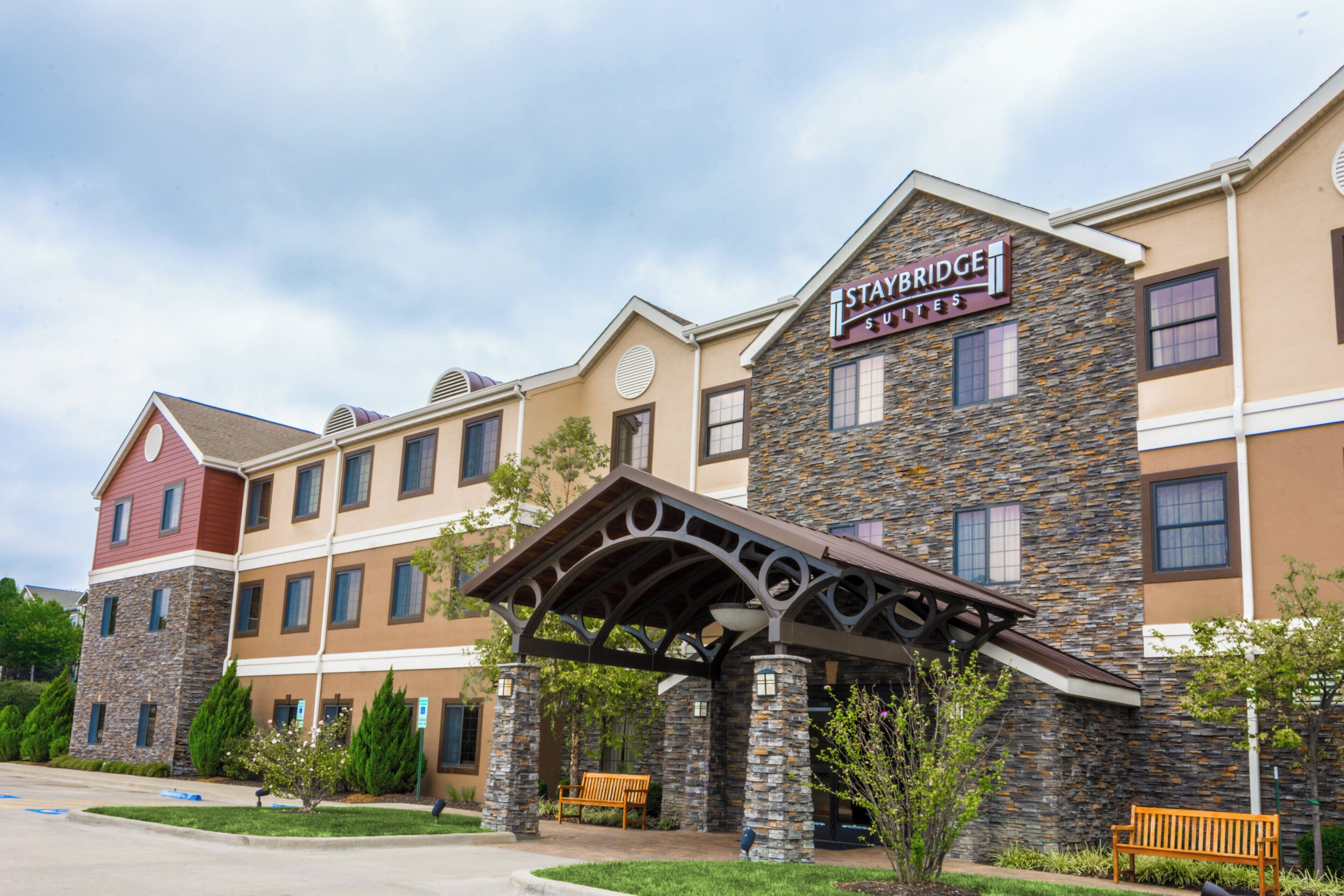 A Staybridge Suites hotel with a stone facade, multiple windows, and a covered entrance.