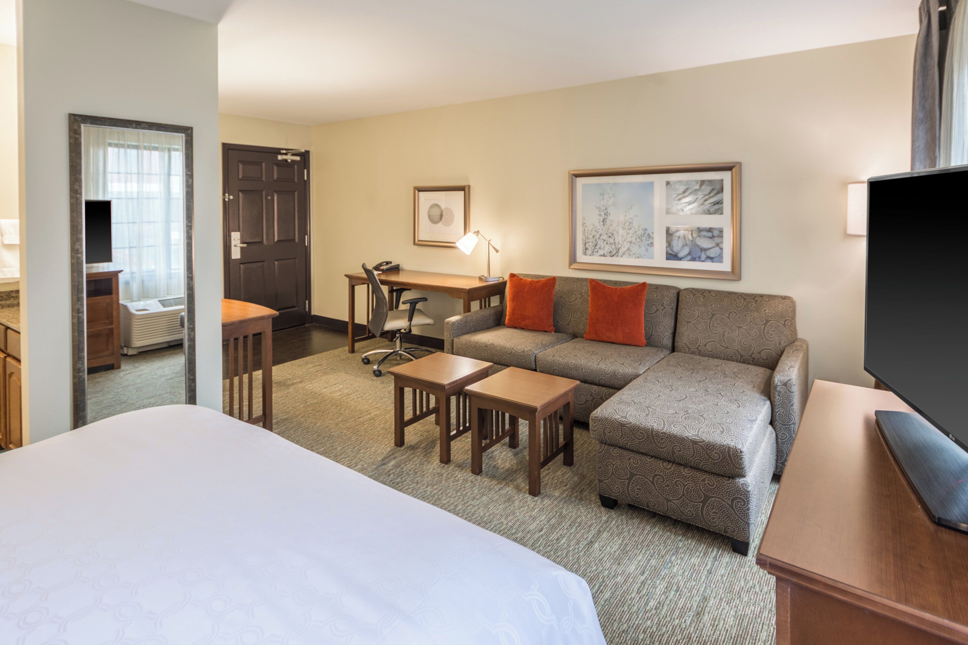 Una habitación de hotel con cama, sofá, escritorio y televisión.