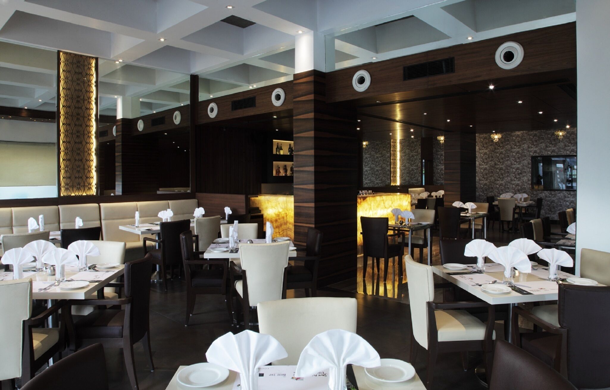 A modern restaurant interior with high ceilings, recessed lighting, and a mix of booth and table seating.
