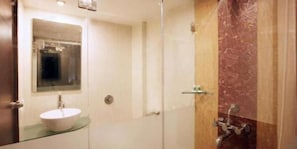Een badkamer met een douchecabine van glas, een wit wastafelmeubel en een spiegel erboven.