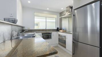 A modern kitchen with stainless steel appliances, granite countertops, and a window providing natural light.