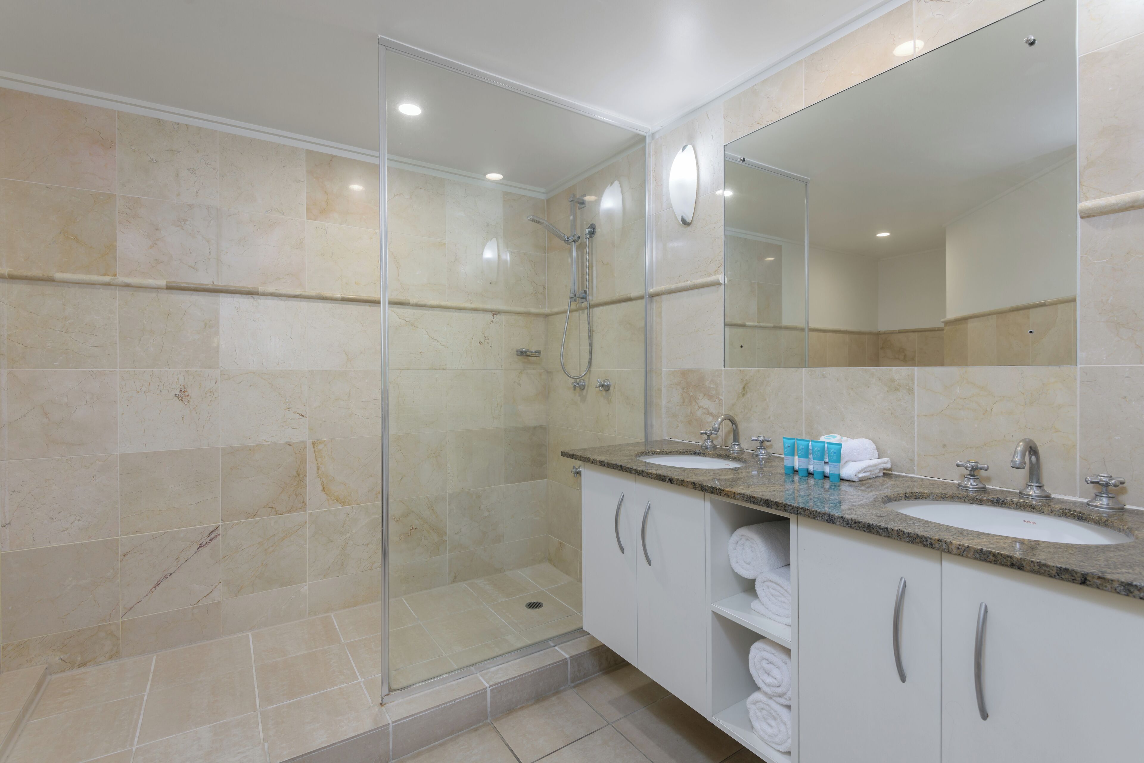 A modern bathroom with a glass-enclosed shower, two sinks, and a large mirror.