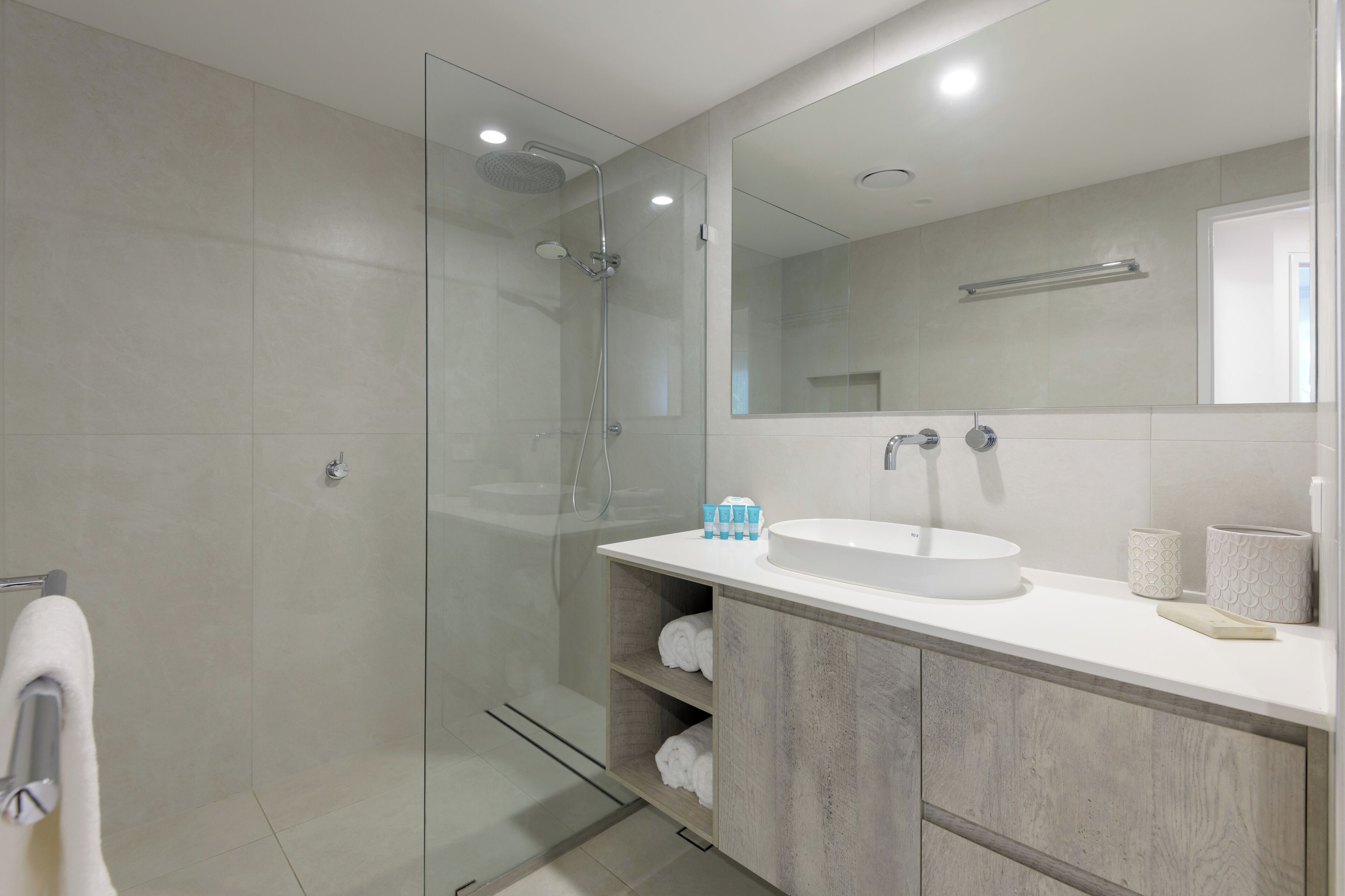 A modern bathroom with a glass-enclosed shower, a white sink, and a large mirror.
