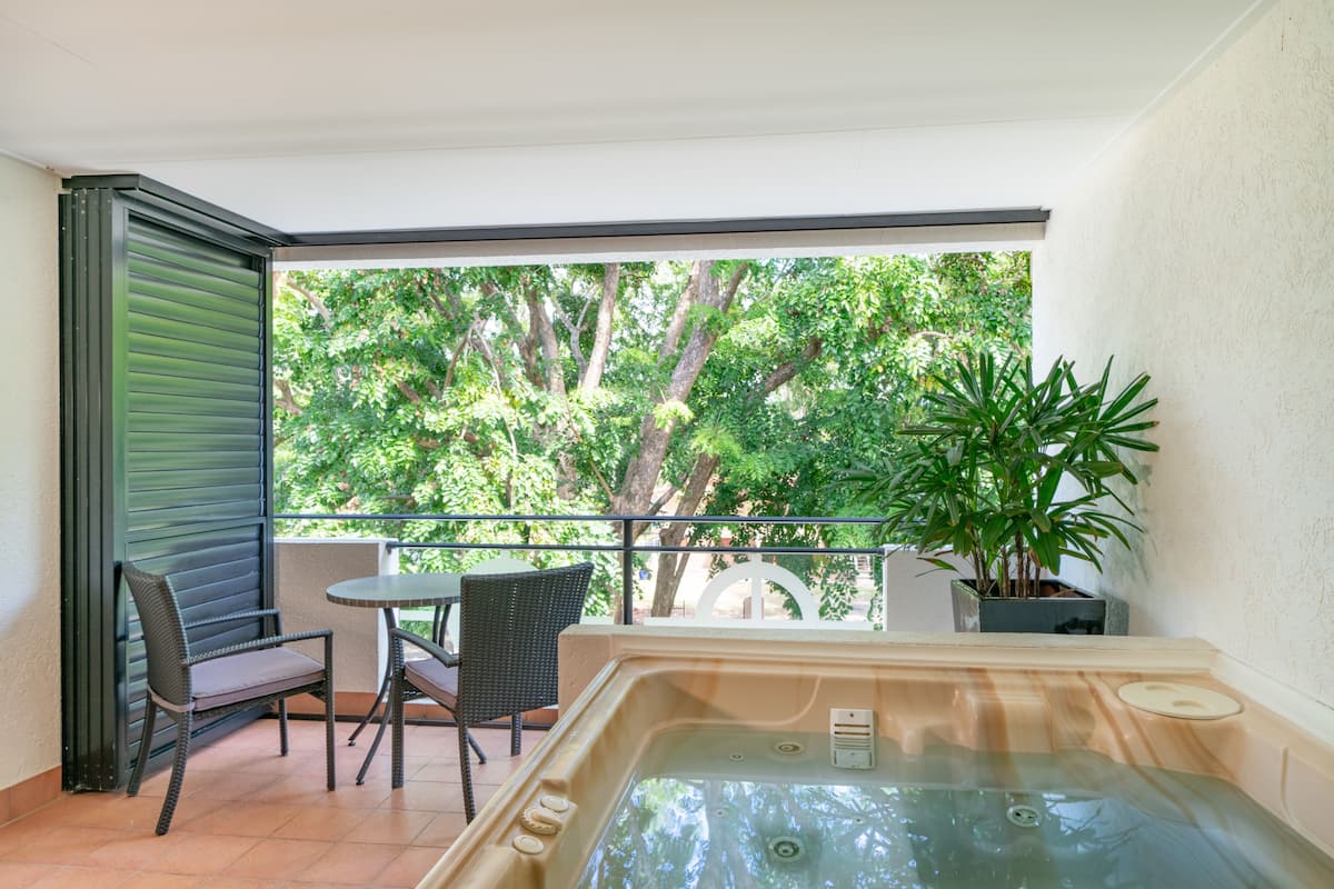 Un balcon équipé d’un jacuzzi, d’une chaise, d’une table et d’un pot de fleurs.
