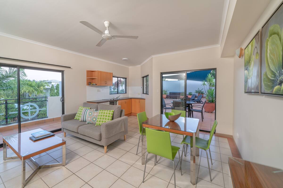 Un salon moderne avec un canapé, une table basse et une table à manger. Il y a un balcon avec du mobilier d’extérieur et une vue sur la ville.