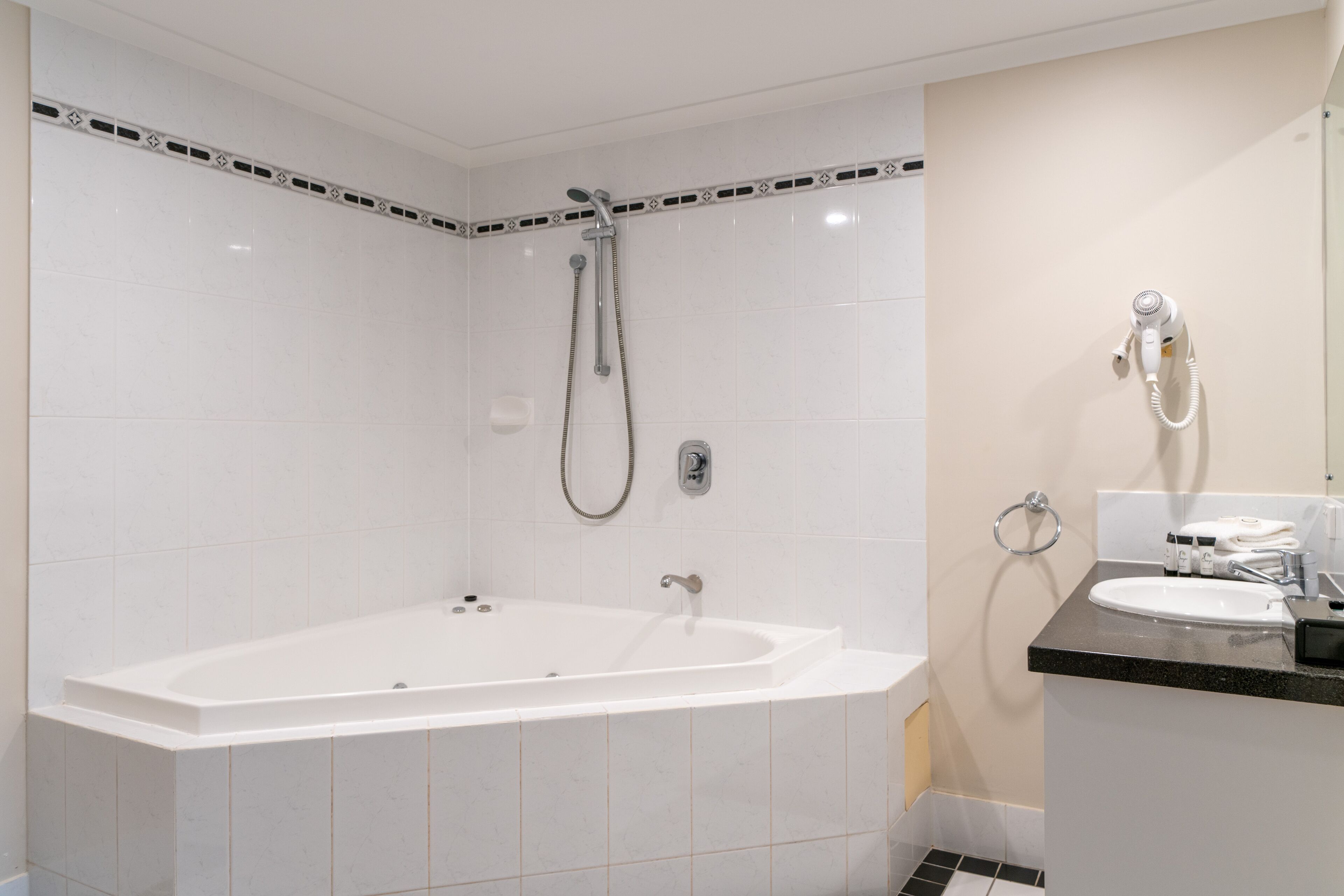 A modern bathroom with a freestanding bathtub, a handheld showerhead, a towel ring, and a sink with a countertop.