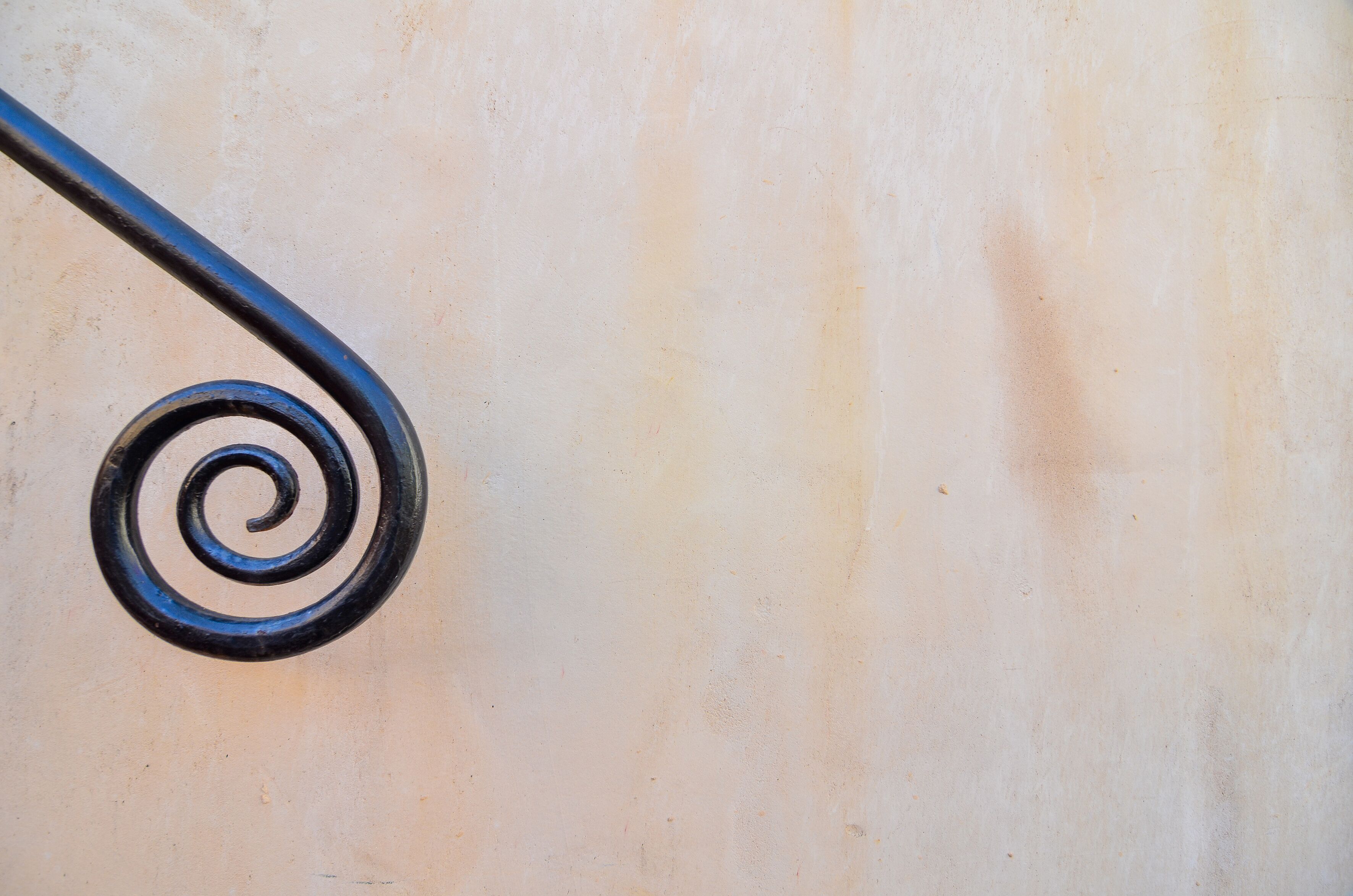A spiral metal railing against a plain wall.