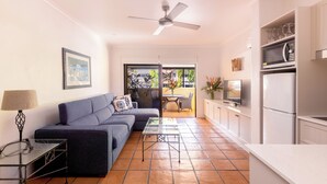 A modern living room with a sofa, a glass coffee table, and a ceiling fan. - Villa San Michele (Port Douglas)