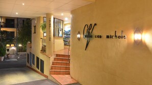 A hotel entrance with a reception desk, a staircase, and a wall with the hotel's name. - Villa San Michele (Port Douglas)