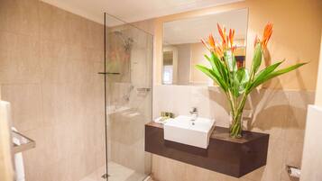 Une salle de bain moderne avec une douche à parois de verre, un lavabo blanc et un miroir au-dessus.