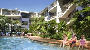 A swimming pool area with lounge chairs and palm trees. - Flynns Beach Resort (Port Macquarie)