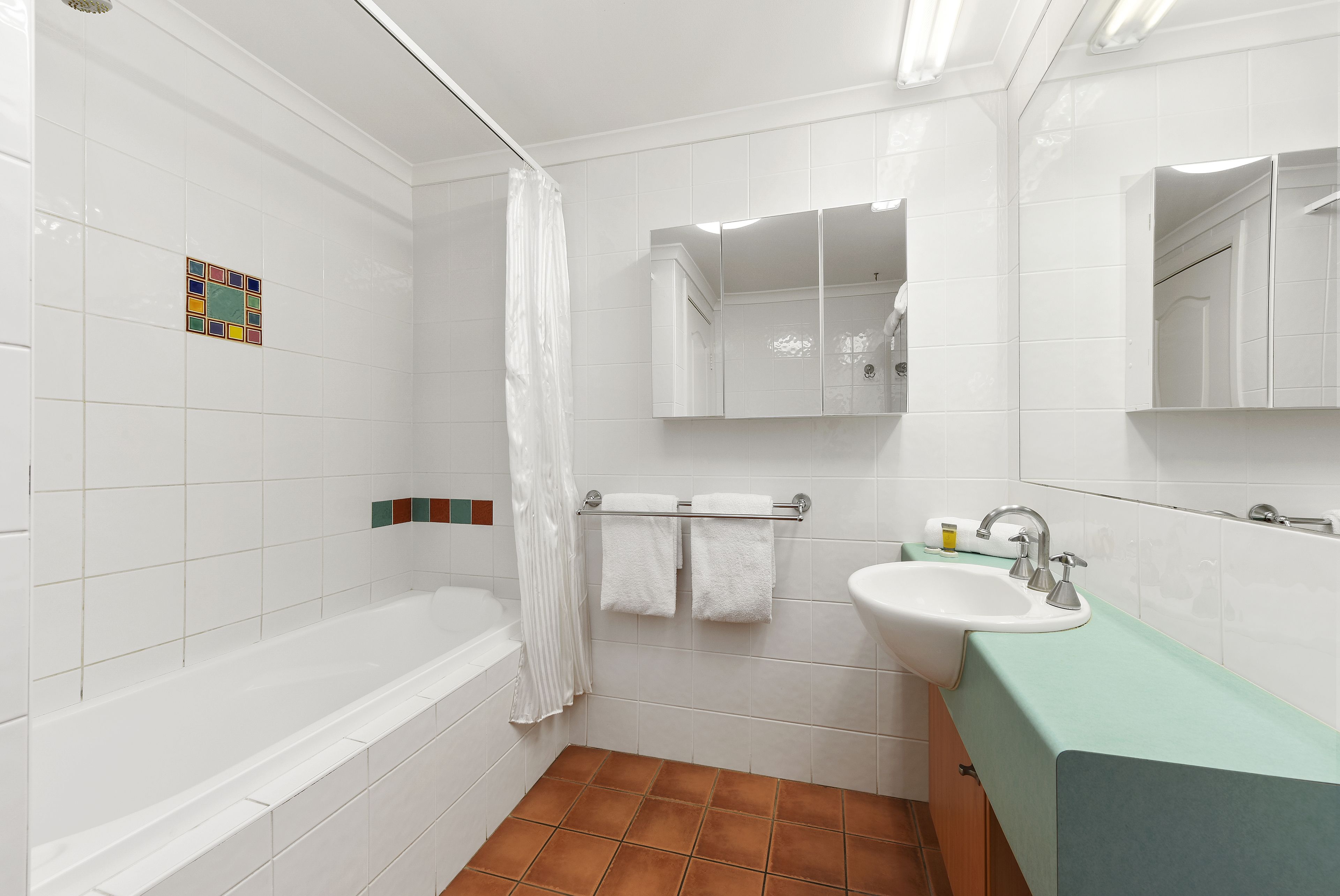 Une salle de bain avec une baignoire, un lavabo, un miroir et un rideau de douche.
