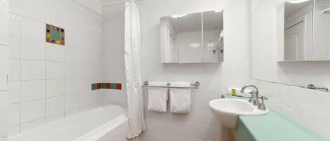 Un baño con bañera, lavabo, espejo y cortina de ducha.