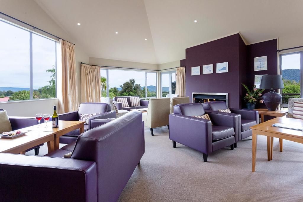 A modern hotel room with a large window, a fireplace, and a seating area with sofas and armchairs.