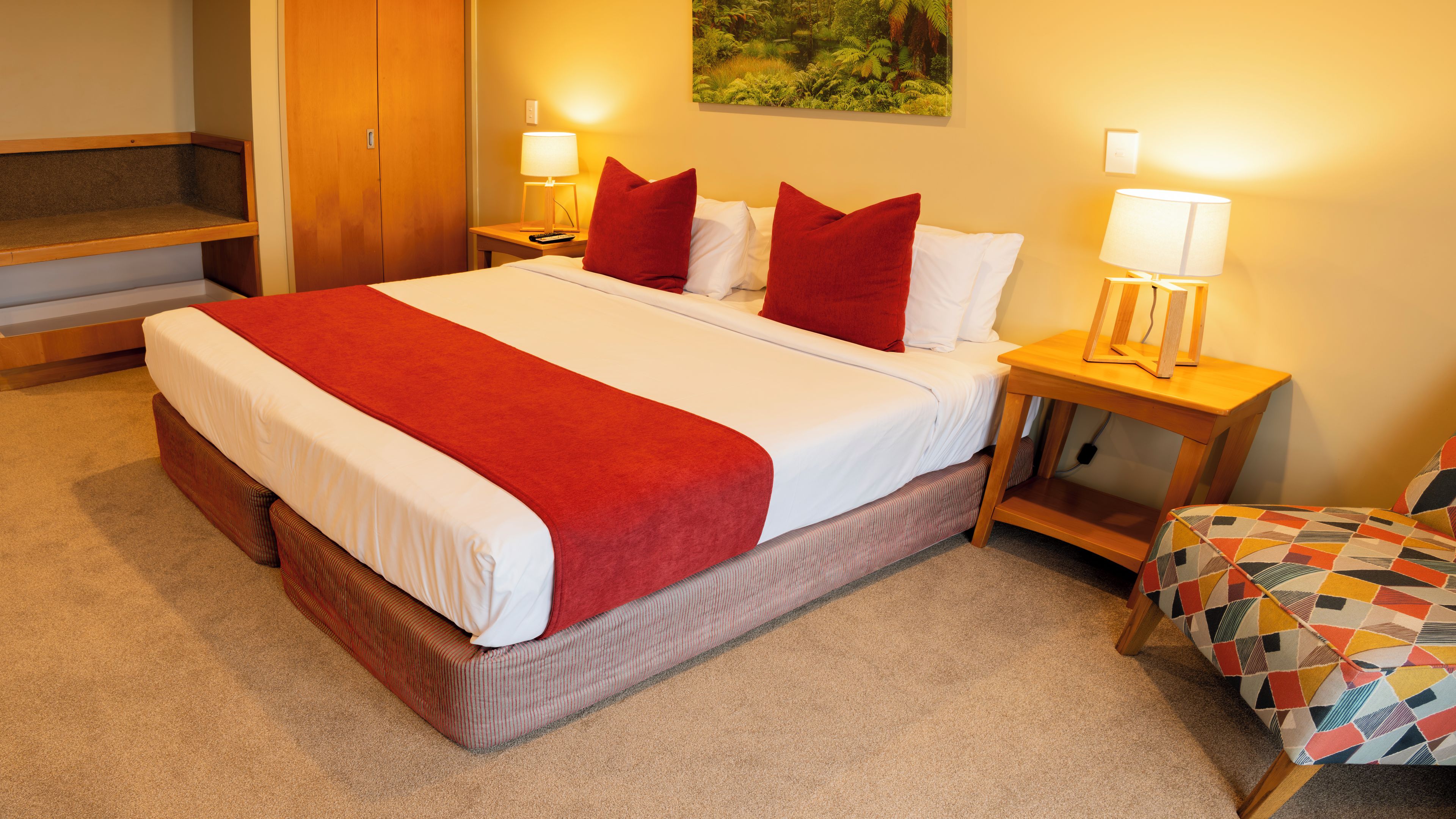 Ein Hotelzimmer mit einem großen Bett, zwei Nachttischen mit Lampen, einem Holzschrank und einer kleinen Couch.