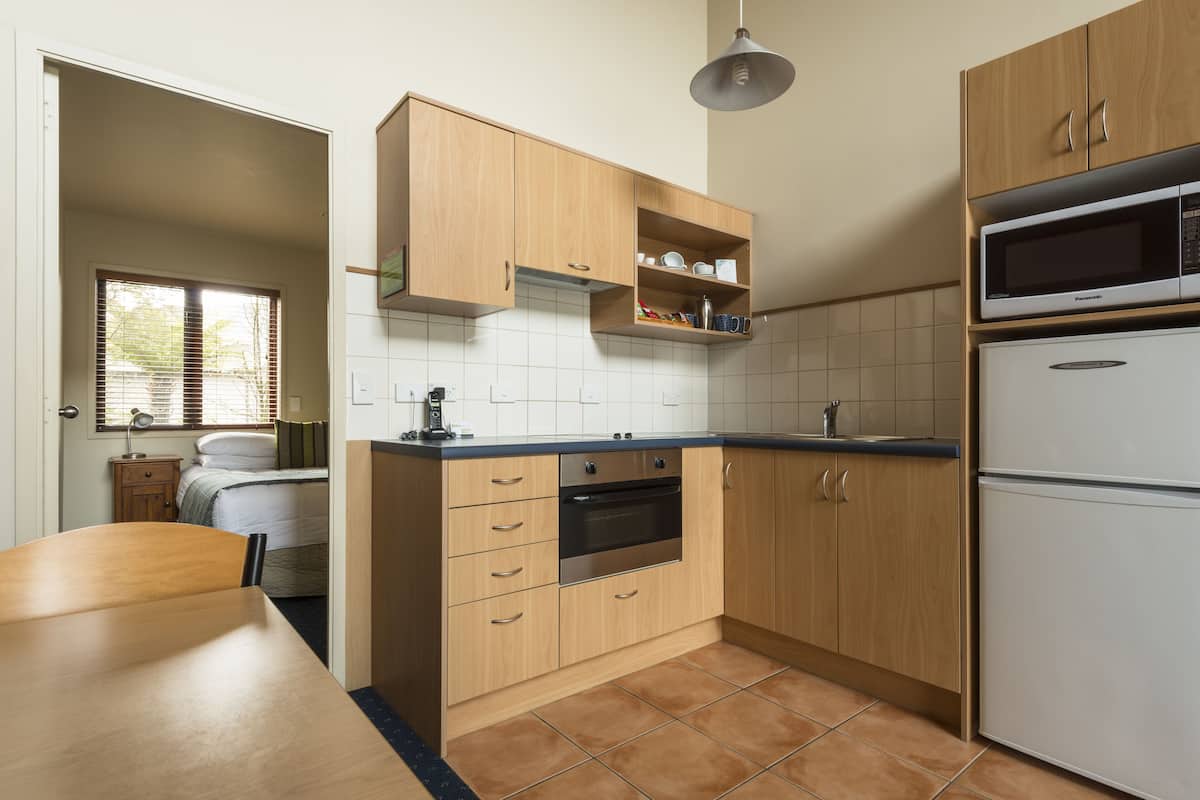Eine kleine Küche mit Holdekor, Backofen, Mikrowelle und Kühlschrank.