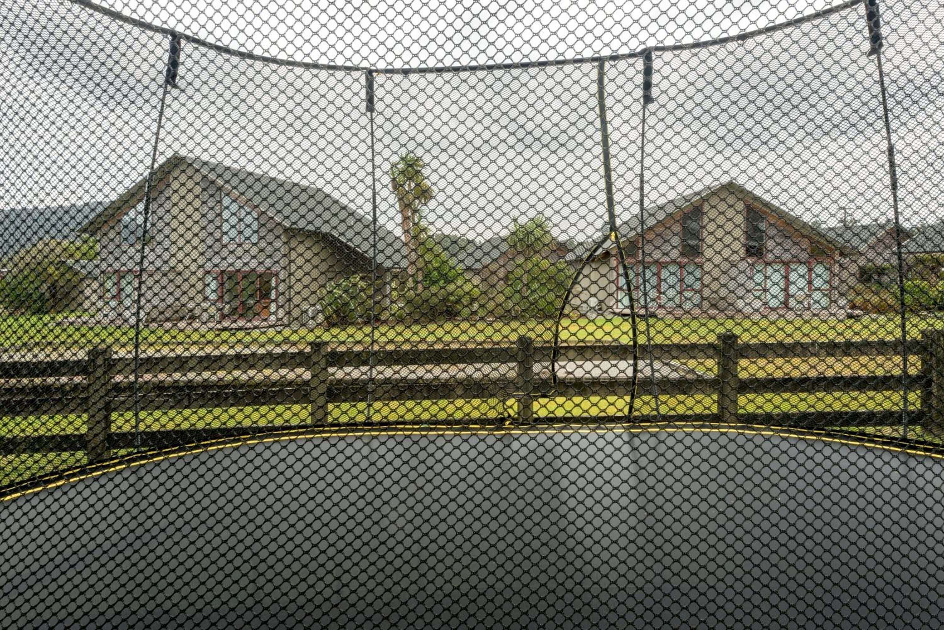 Un espace clos, doté d’un terrain de basketball, entouré de bâtiments et d’un champ d’herbe.