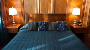 A hotel room with a large bed, two bedside tables with lamps, and a wooden headboard.