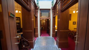 A hotel corridor with wooden doors, a red carpet, and a patterned floor.