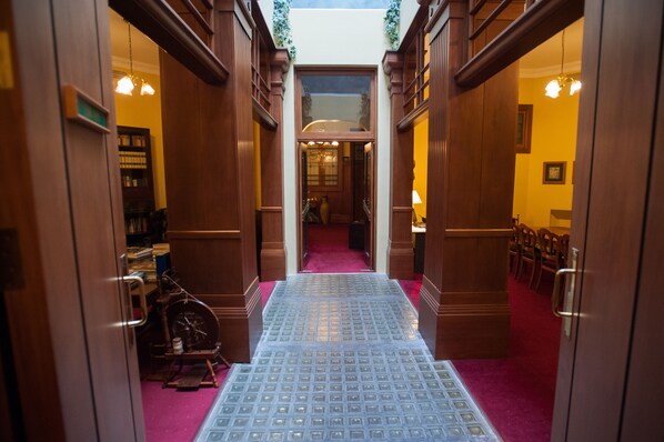 A hotel corridor with wooden doors, a red carpet, and a patterned floor. - The County Hotel (Napier)