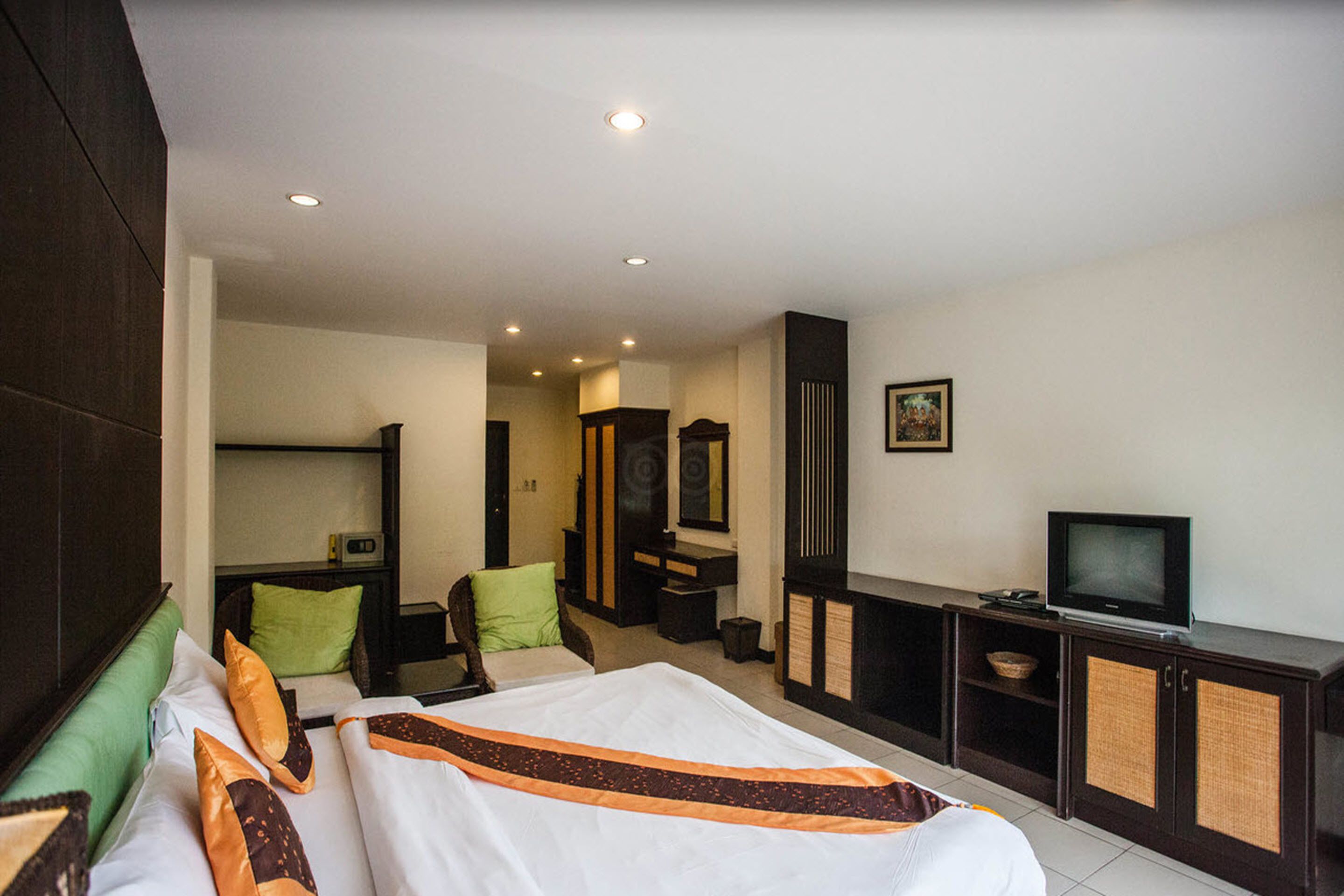 Ein Hotelzimmer mit einem großen Bett, einem Fernseher, einem Schreibtisch und einem Schrank.