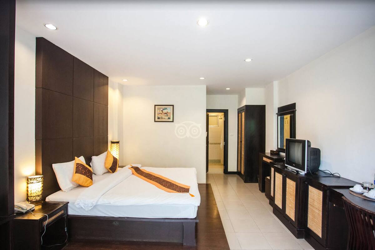 Une chambre d’hôtel moderne avec un grand lit, des lampes de chevet, une télévision et un bureau avec une chaise.