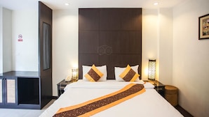 Een hotelkamer met een groot bed, twee nachtkastjes met lampen, een donker hoofdeinde en een ingelijst schilderij aan de muur.