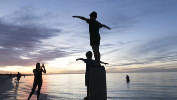 A beach scene with a wooden post and a statue of a person standing on it.