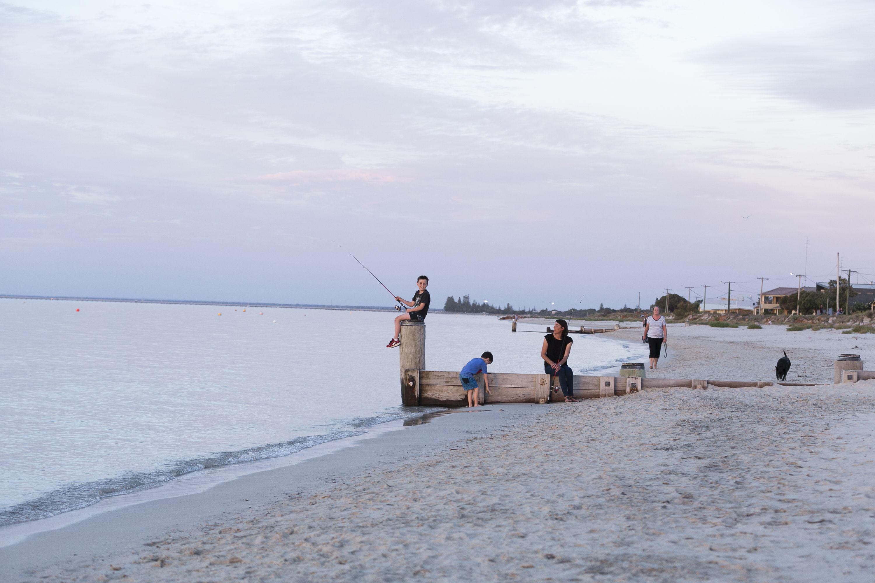 A beach with people fishing and walking along the shore.