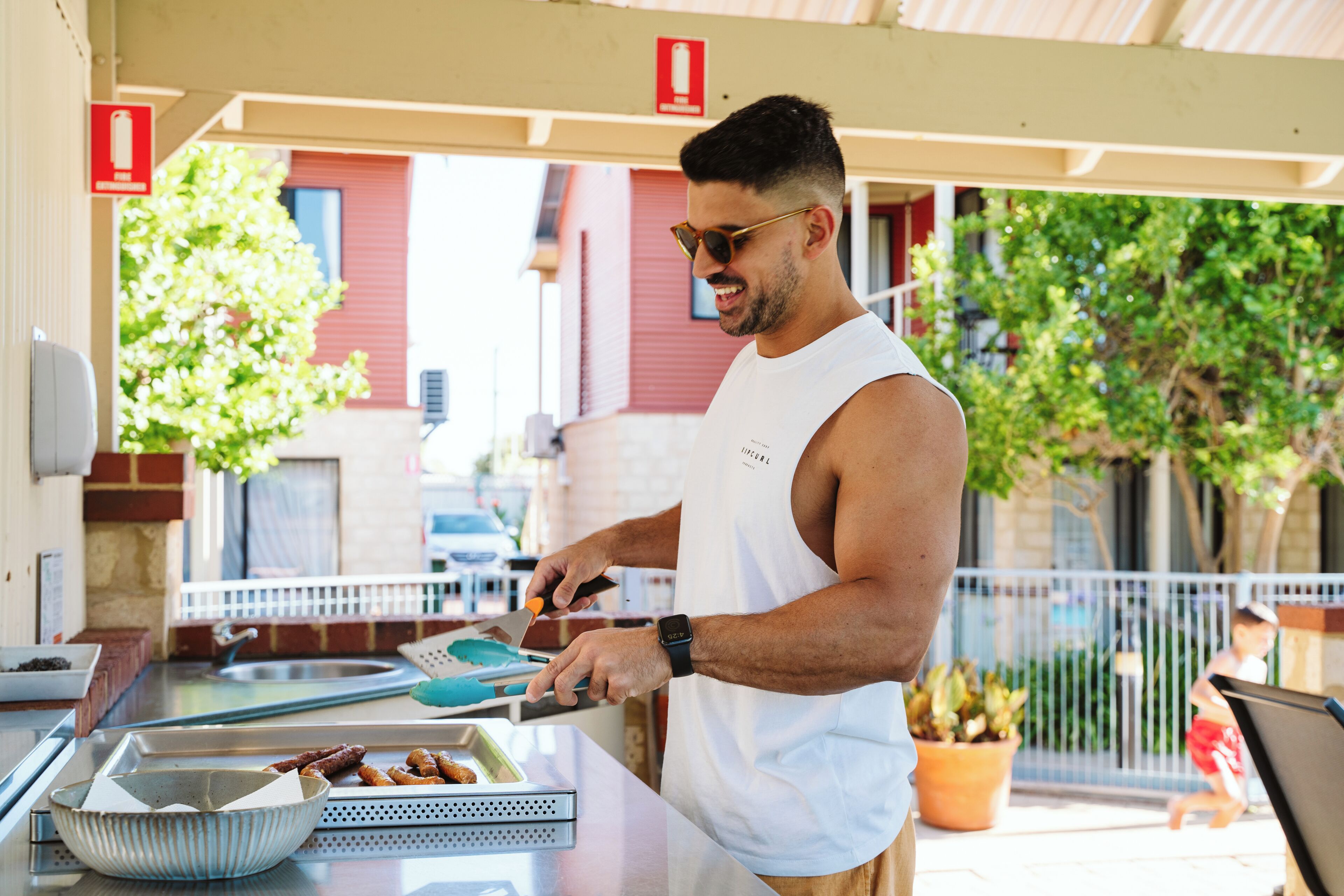 Una persona prepara cibo a un bancone all'aperto, con un vassoio metallico e una ciotola.