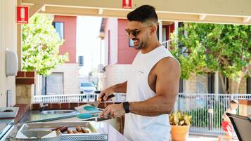 Una persona prepara cibo a un bancone all'aperto, con un vassoio metallico e una ciotola.