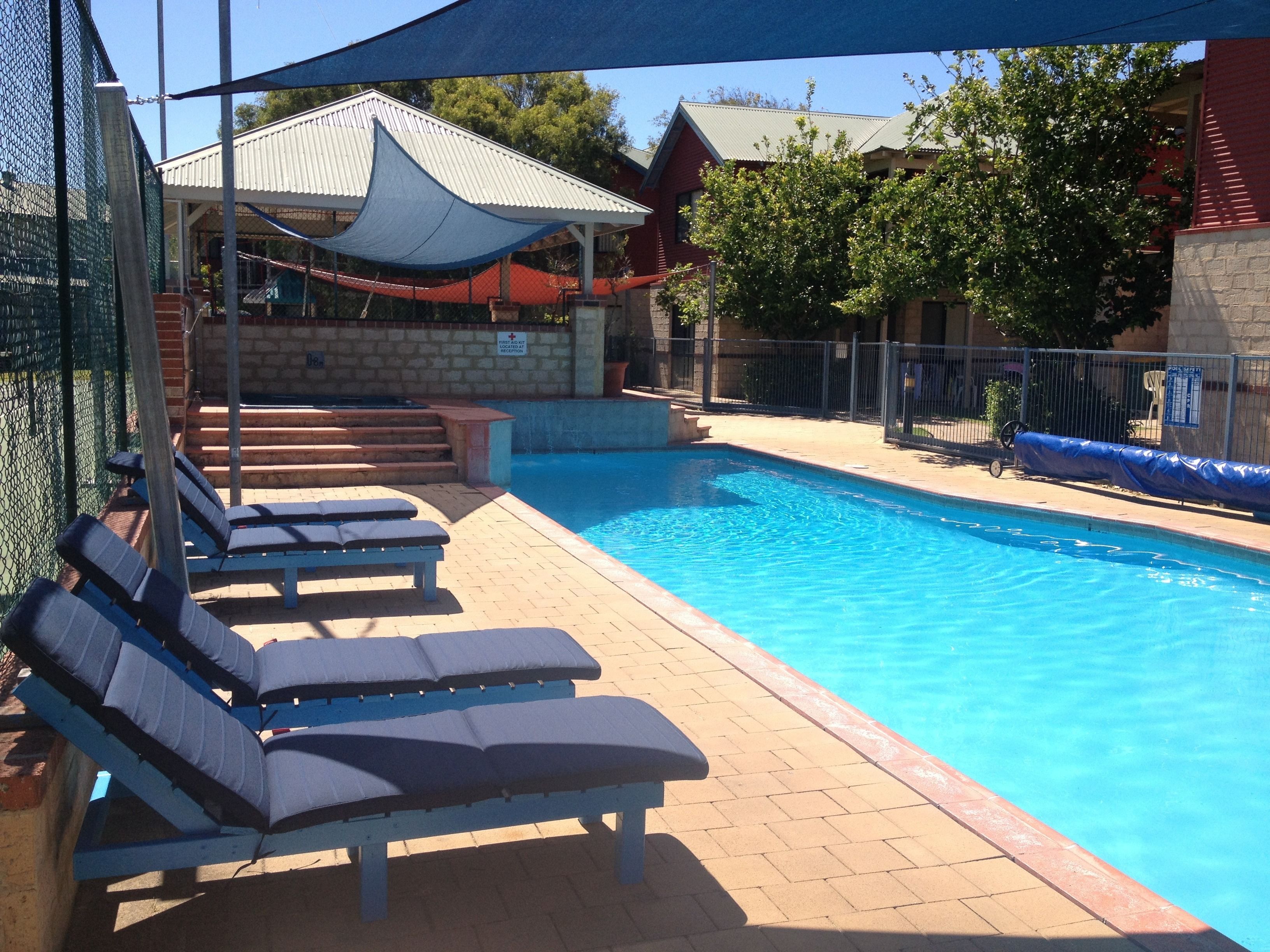 A swimming pool with lounge chairs and a covered seating area.