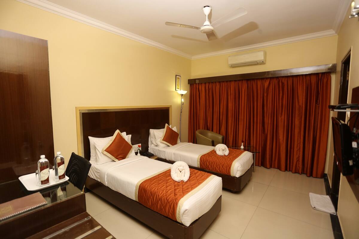 A hotel room with two beds, a desk, and a chair.