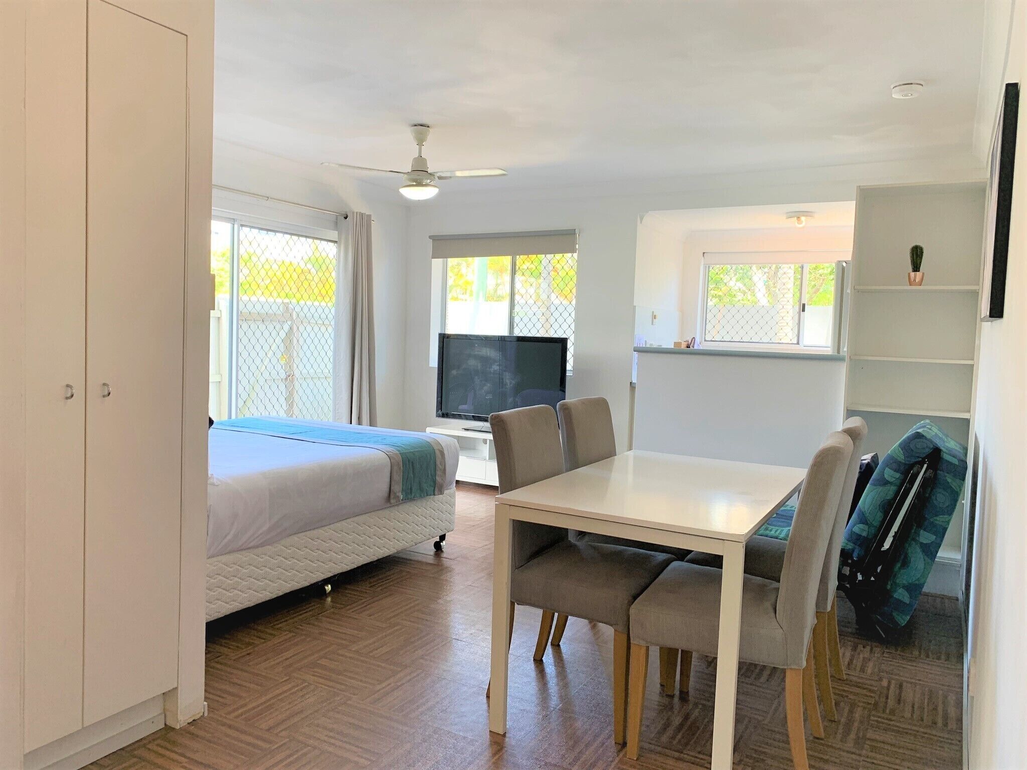 Una habitación compacta con cama, televisión, mesa de comedor y sillas.