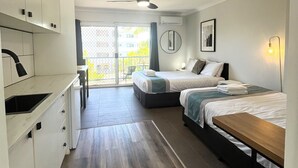 A modern hotel room with a kitchenette, two beds, a ceiling fan, and a balcony with a view. - Broadwater Keys (Labrador)