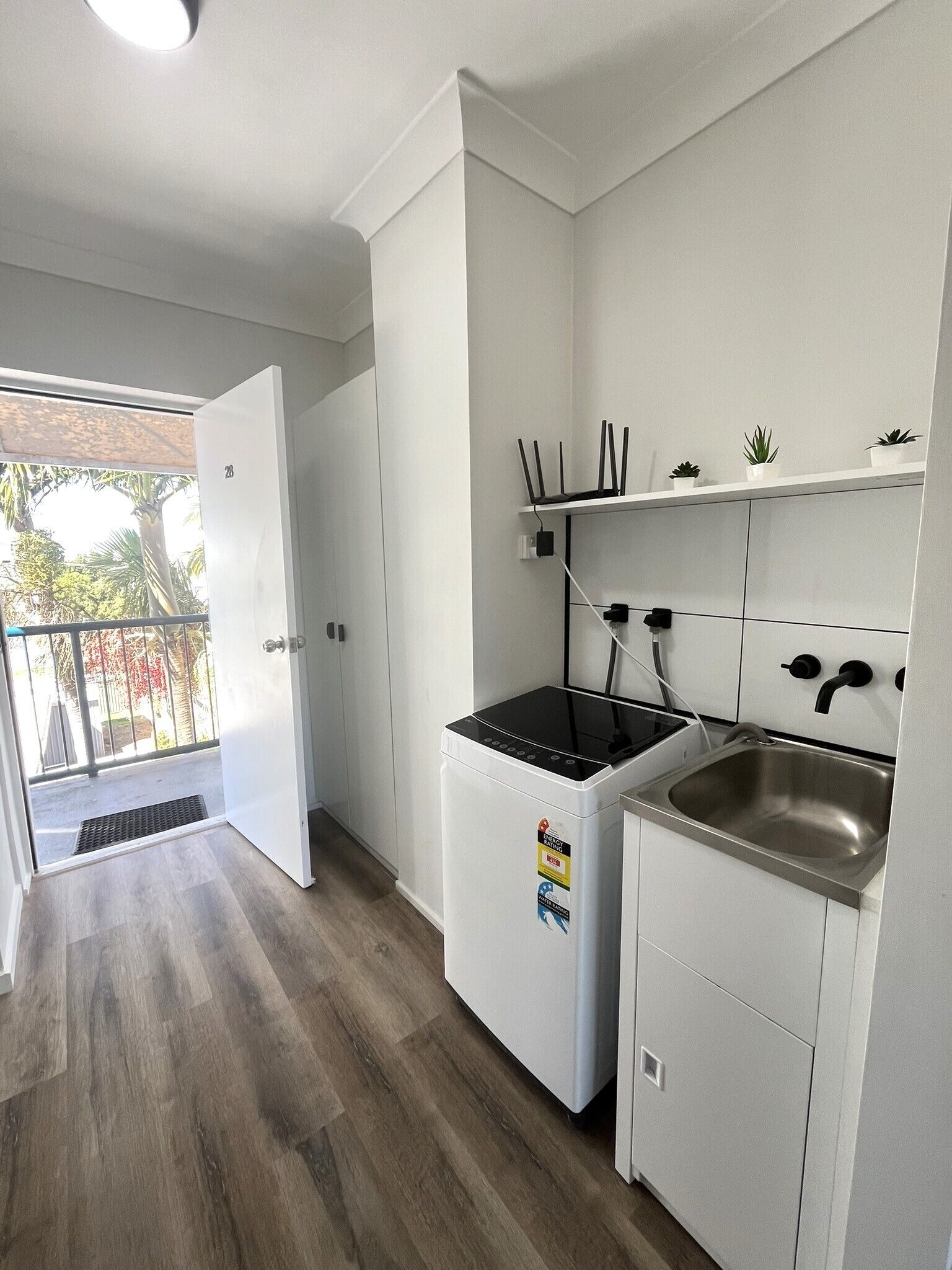A compact kitchen with white cabinets, a built-in stove, and a stainless steel sink.