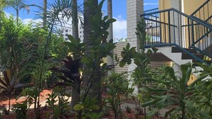A multi-story building with a staircase and a garden with palm trees and various plants. - Broadwater Keys (Labrador)