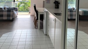 A modern kitchen with white cabinets, a built-in oven, and a dining area with a checkered sofa and chairs. - Broadwater Keys (Labrador)