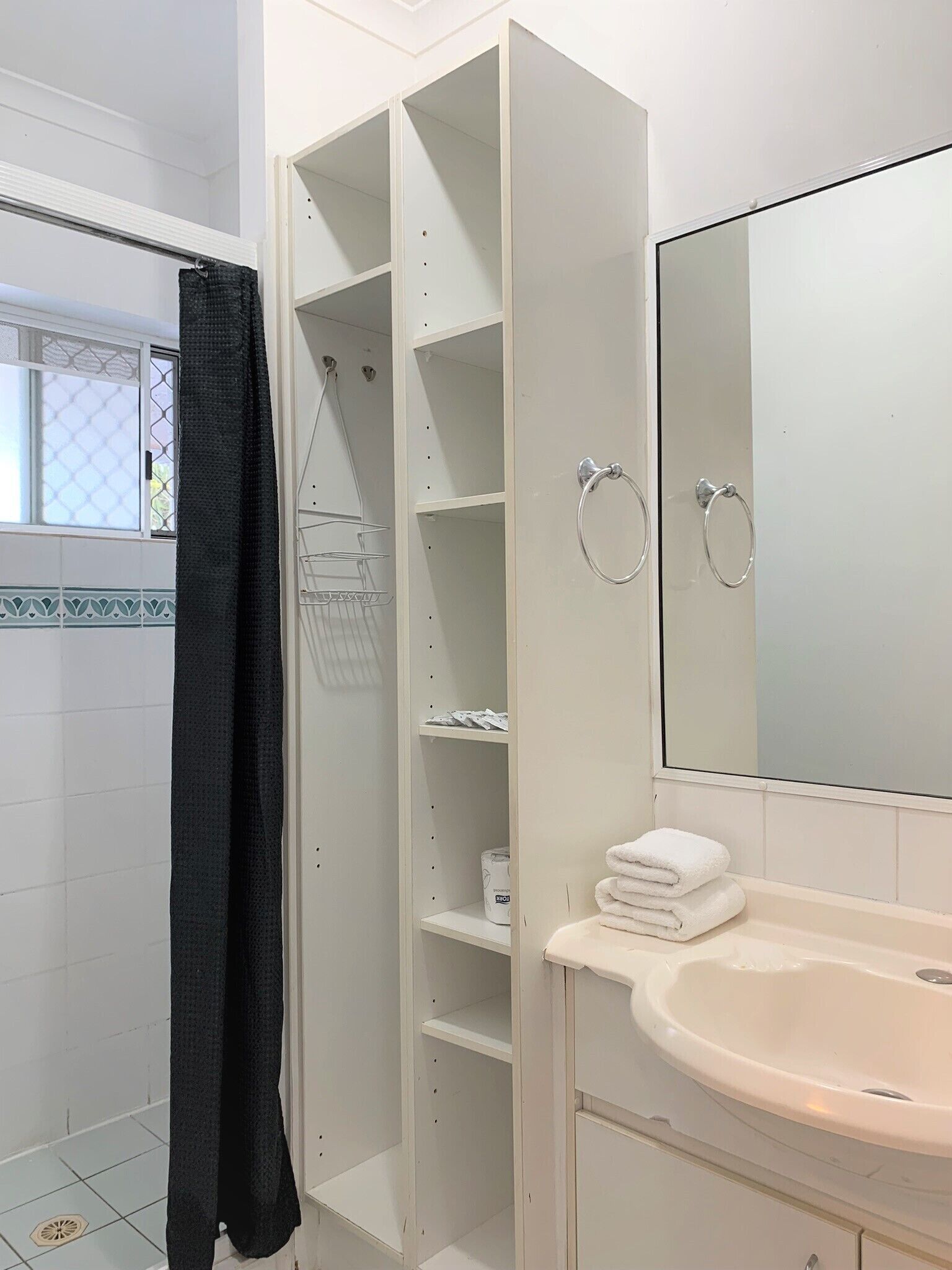 A bathroom with a white sink, a mirror, a towel rack, and a shower curtain.