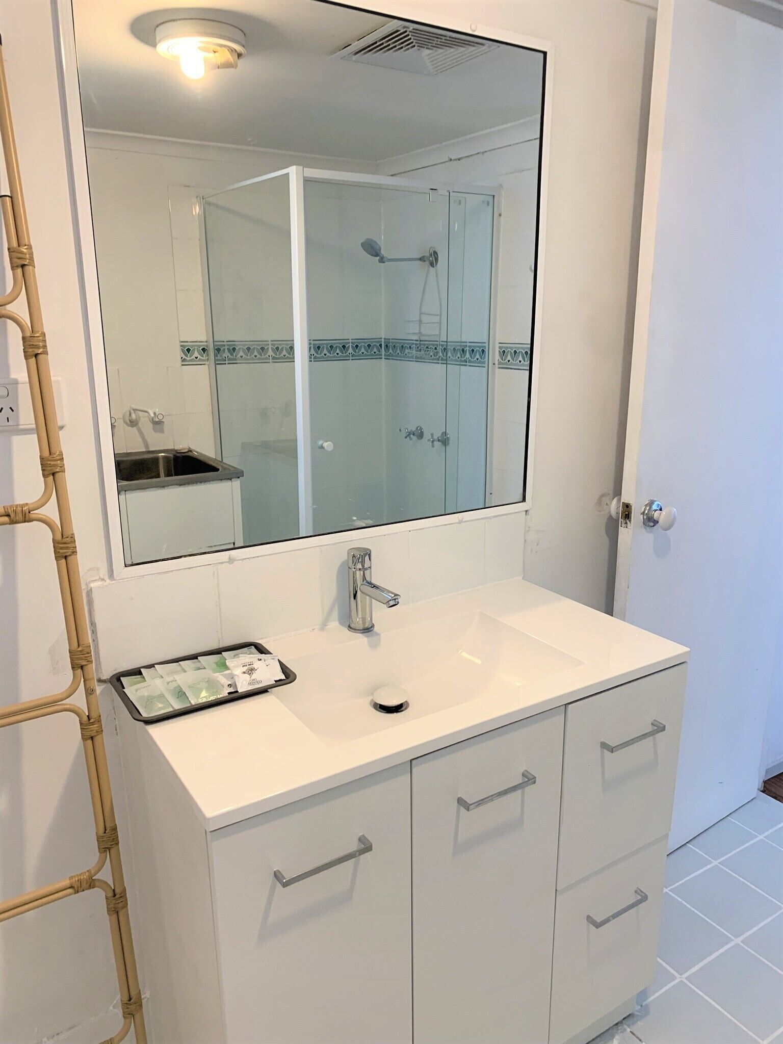 A bathroom with a white vanity, a large mirror, and a glass-enclosed shower.