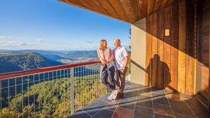 A couple standing on a balcony with a view of a mountainous landscape. - Binna Burra Sky Lodges (Binna Burra)