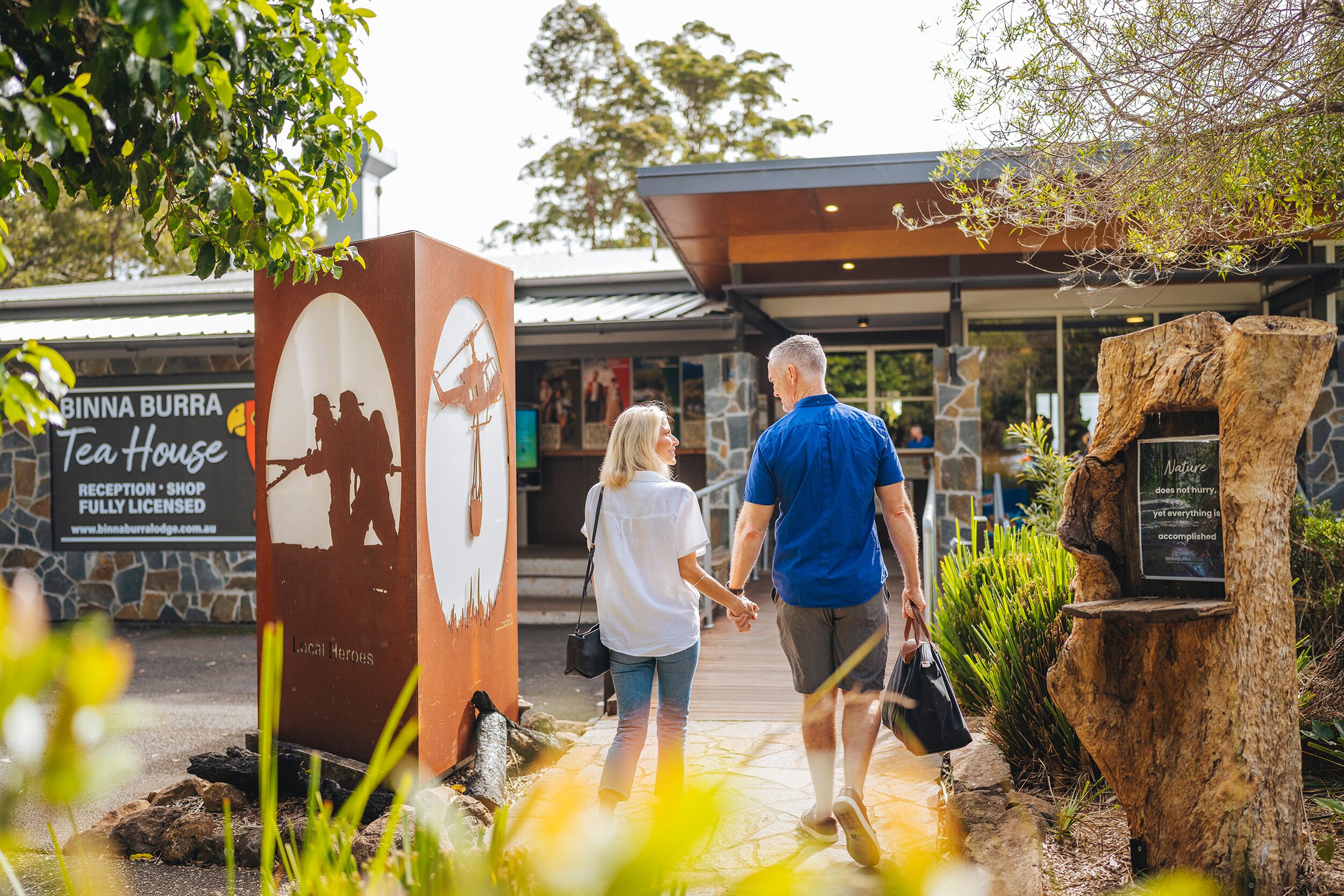 Et par går hen mod en bygning med et skilt, der viser 'BINNA BURRA Tea House'.