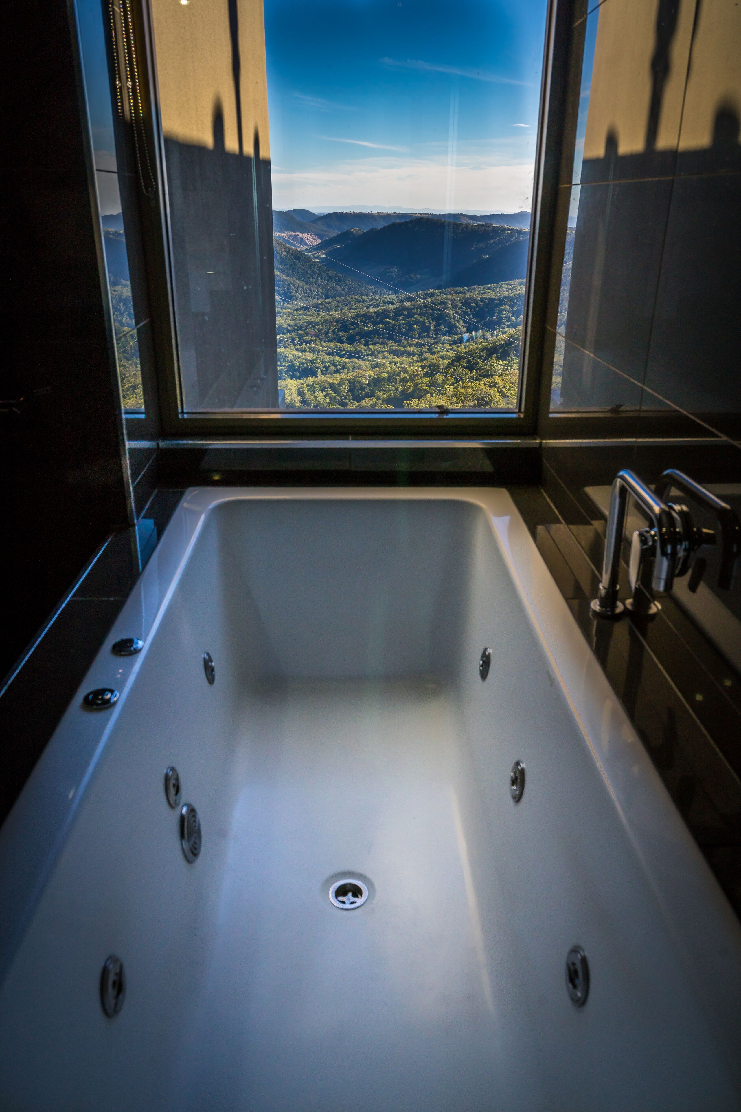 Une salle de bain moderne dotée d’une grande baignoire, offrant une vue sur un paysage montagneux grâce à une grande fenêtre, et présentant un design épuré et contemporain.