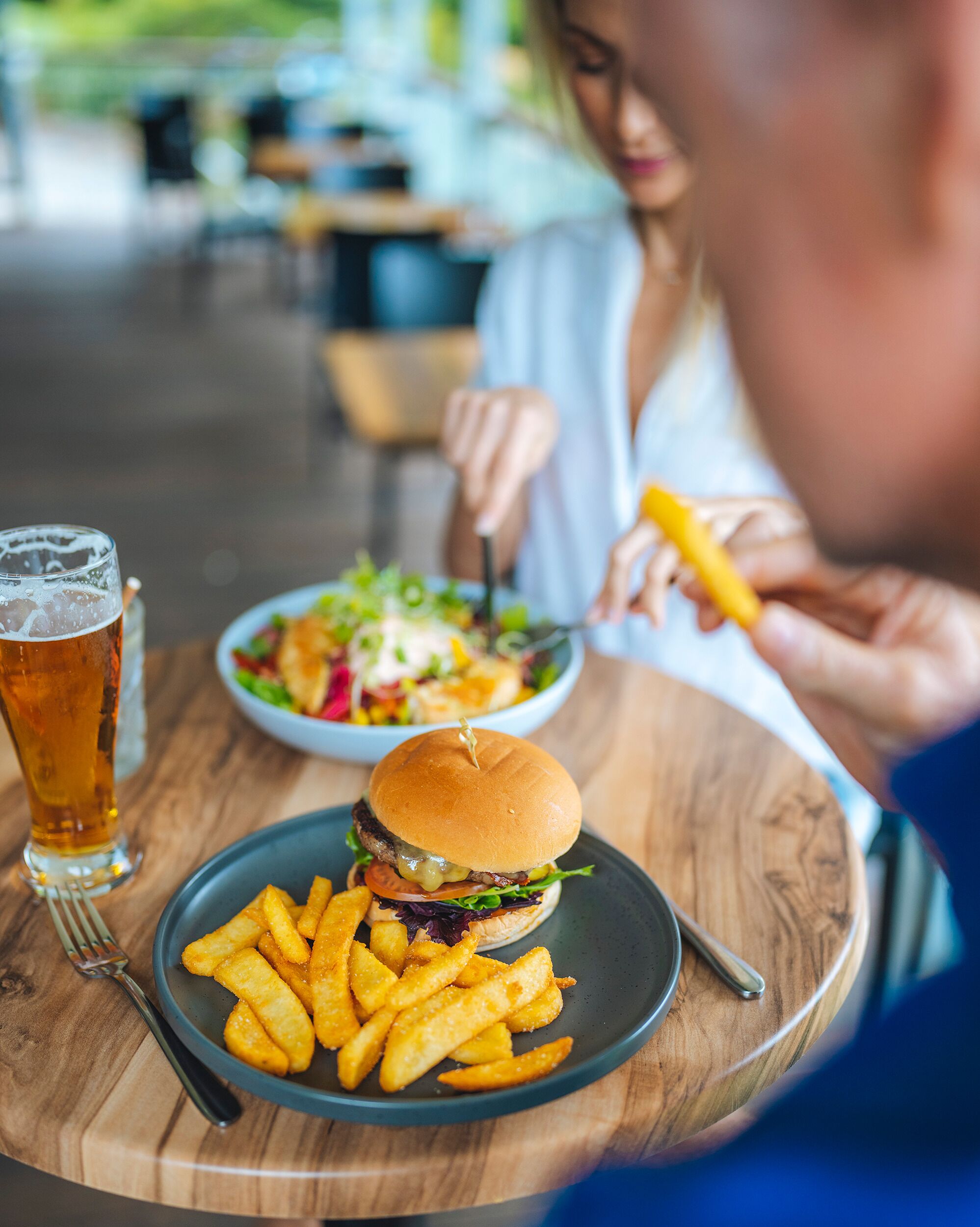 A dining table with a burger, fries, and a drink.
