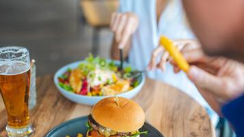 A dining table with a burger, fries, and a drink.