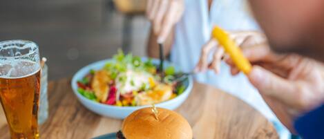 Una mesa de comedor con una hamburguesa, papas fritas y una bebida.