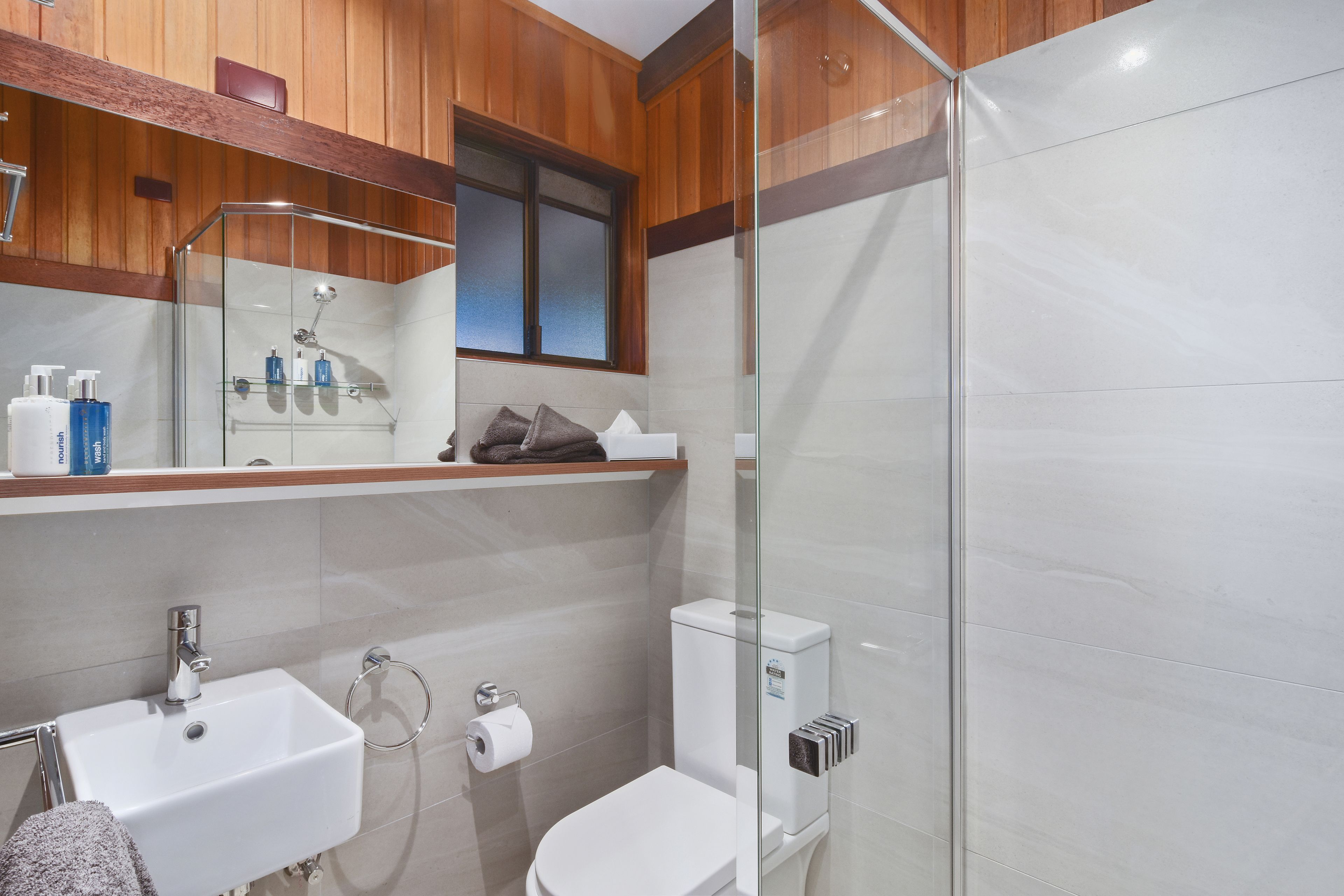 A modern bathroom with a glass-enclosed shower, a white sink, and a toilet.