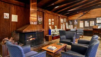 A cozy room with a fireplace, wooden walls, and blue patterned furniture.