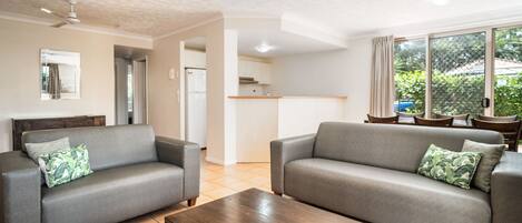A living room with two grey sofas, a wooden coffee table, and a ceiling fan.