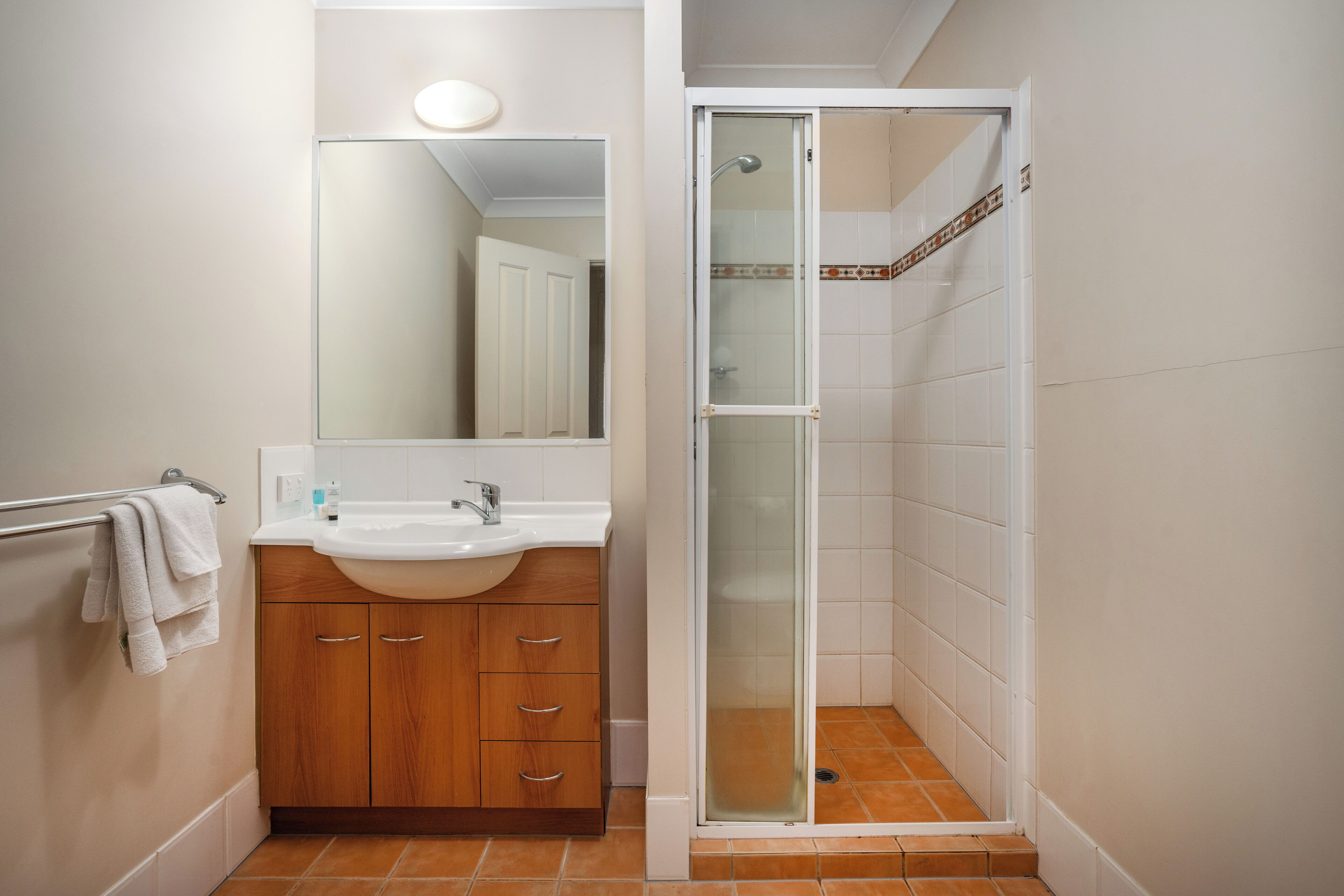 A bathroom with a wooden vanity, a sink, and a glass-enclosed shower.